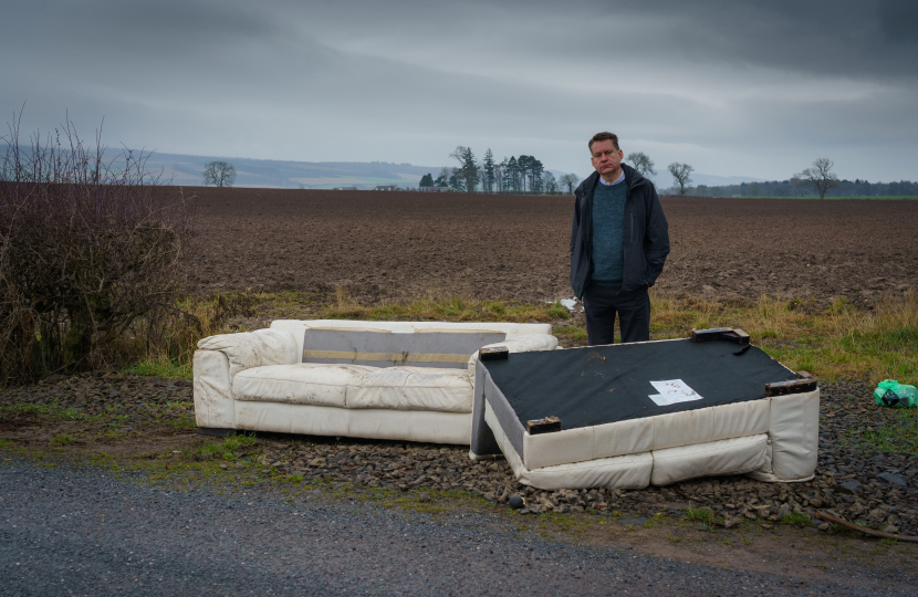 Murdo Fraser MSP beside some fly-tipping